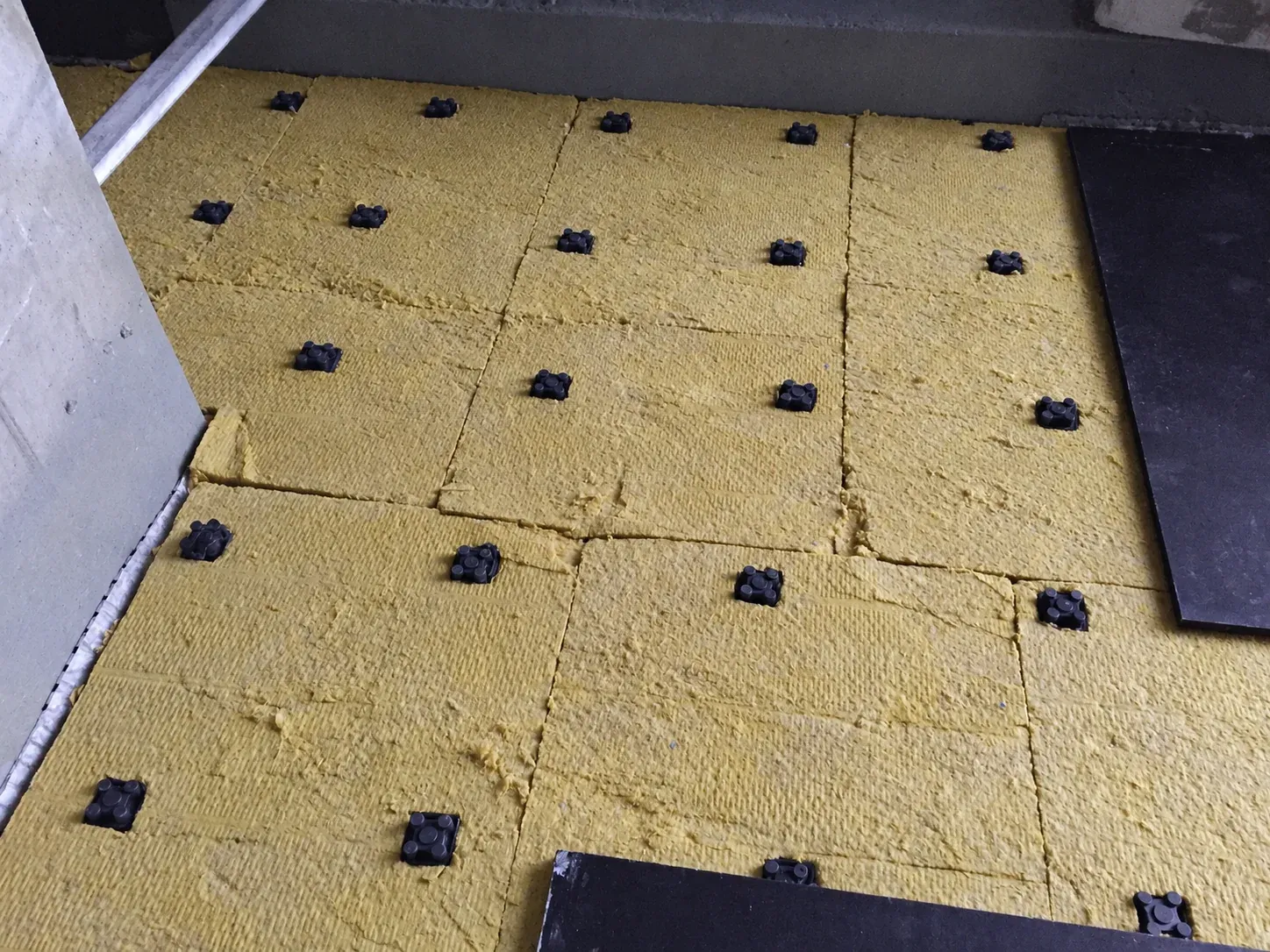 AFR-R floating floor mounts set out on the structural slab, with mineral wool between them and plywood going down on top