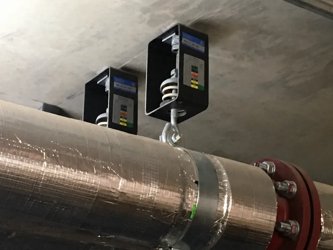 Two AH-S housed spring hangers carrying an insulated pipe below the slab