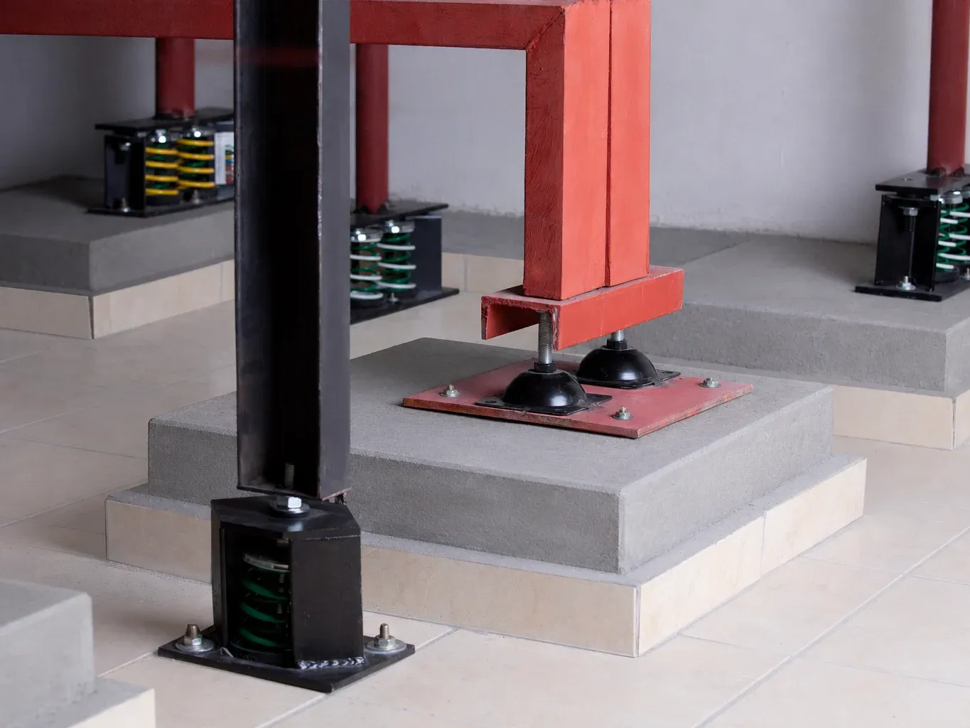 ASI-R housed rubber mounts under a steel frame, with housed seismic spring isolators on the plinths around it
