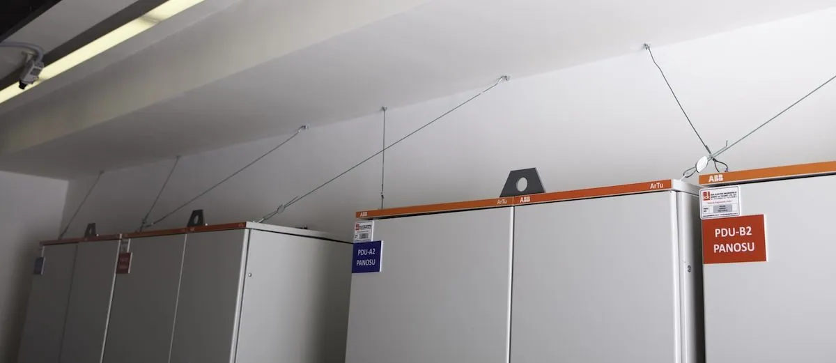 Wire-rope seismic restraints securing the tops of PDU and switchgear cabinets