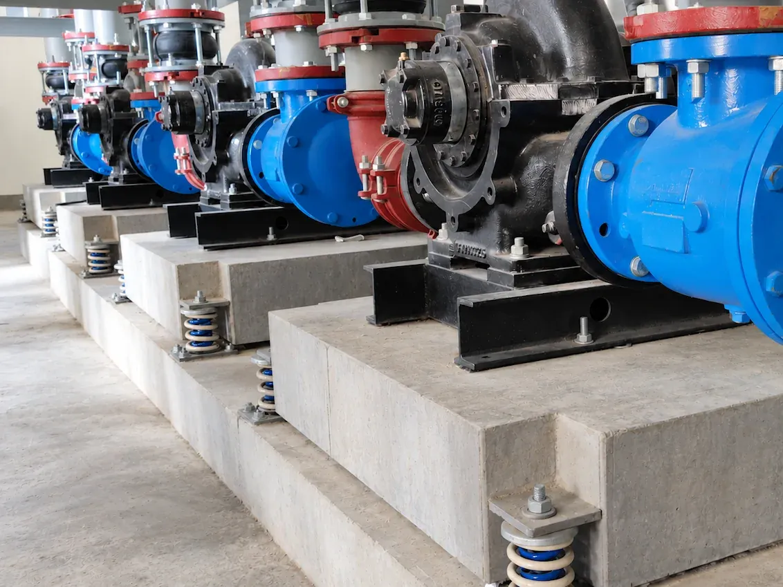 Row of split-case pumps, each on a concrete inertia base carried by open spring isolators at its corners, Granada Mall, Riyadh